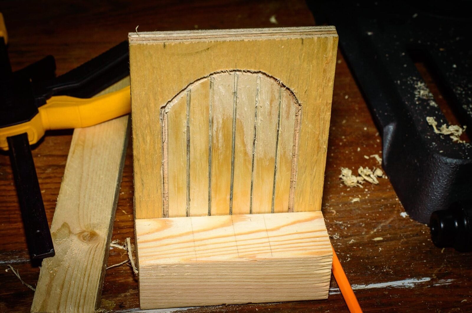 The recessed arch with a deeper outline, plank grooves, and a 2×4 base marked for cutting
