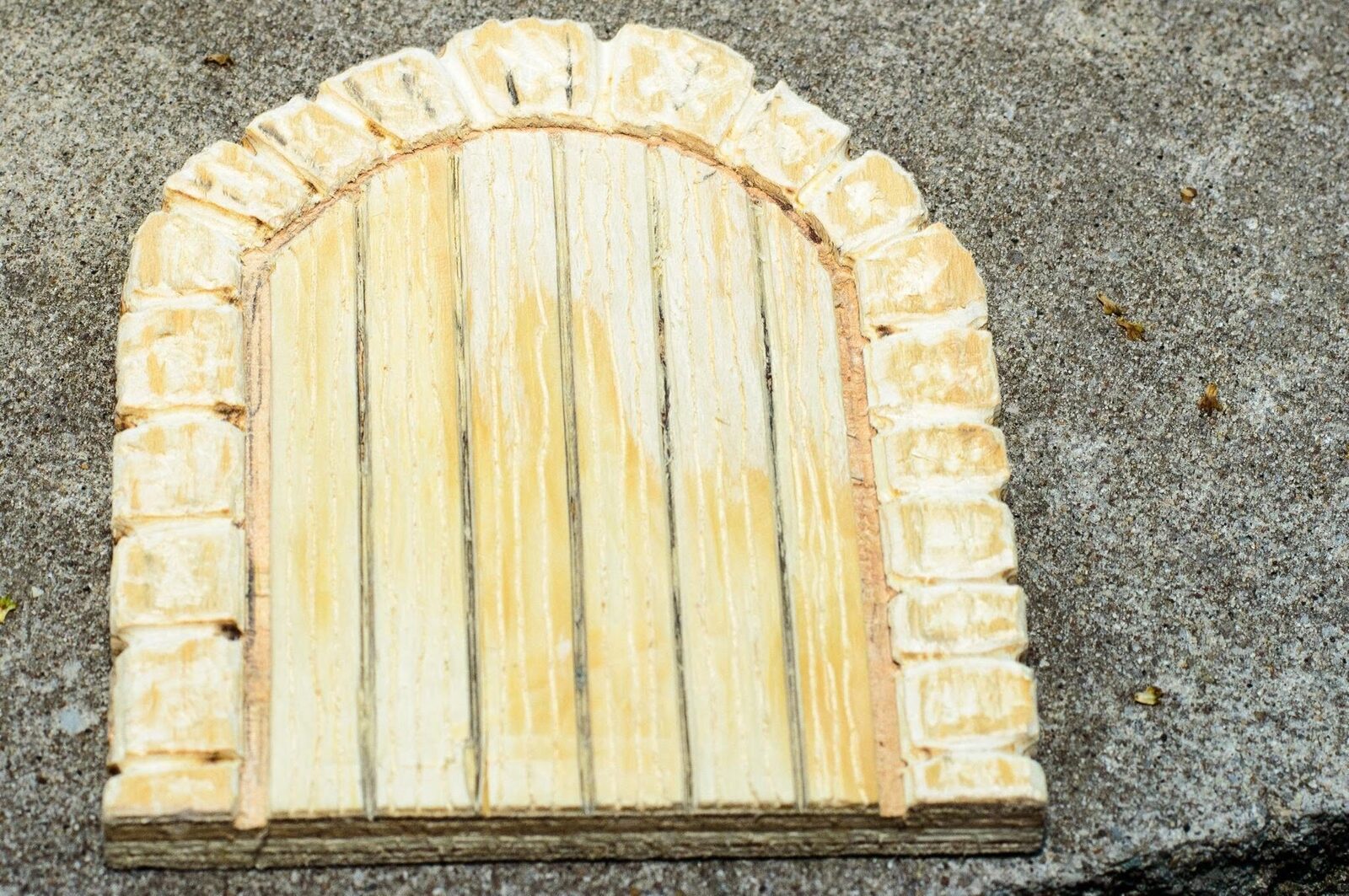 Unpainted plywood door surrounded by individually carved wooden stones