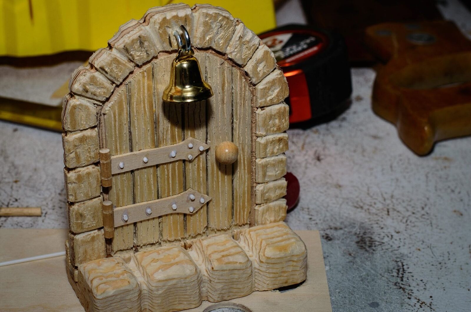 Unpainted door fitted with handmade basswood hinges, styrene bolt heads, a round knob and a small bell